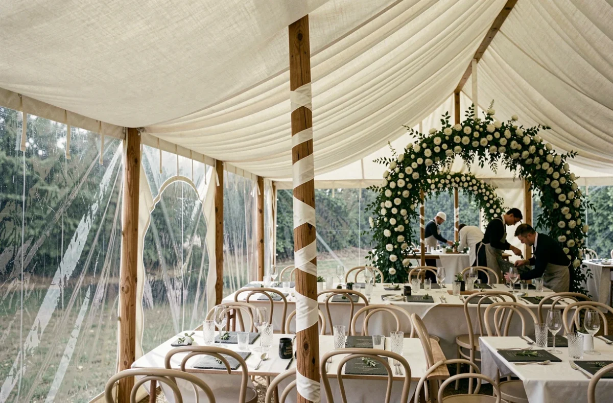 Intérieur détaillé d'un chapiteau de mariage parisien avec chaises bentwood et arche florale en cours d'installation
